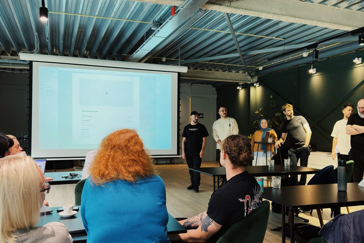 Präsentation in einem Seminarraum: Deckenprojektor und Leinwand, davor sitzende Zuhörer und stehende Personen